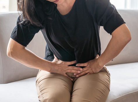 Women with IBD or IBS clutching her stomach.