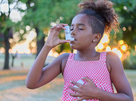 Young girl using an inhaler outside