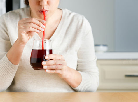 Women sipping cranberry juice through a straw
