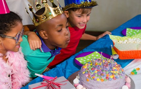 Kids blow out candles on a birthday cake