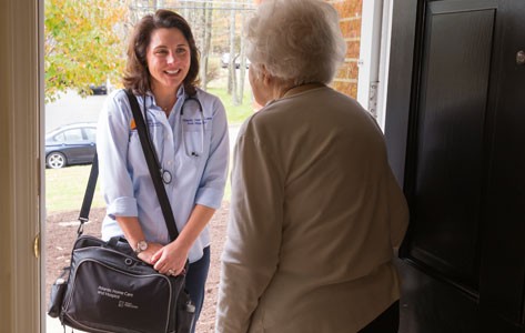 Older woman greets a young, home-health aide at the door.