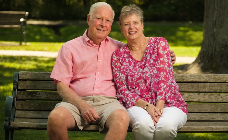 Former DBS patient sits on park bench with husband