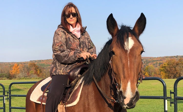 Jill sits on a horse af her farm after recovering from spine surgery.