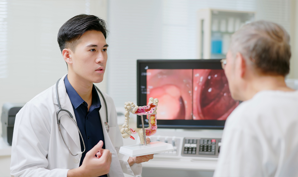 Doctor showing a patient a colon anatomy model.
