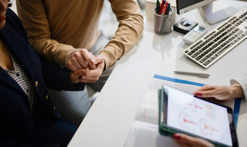 A doctor holding a uterus diagram while speaking with a patient