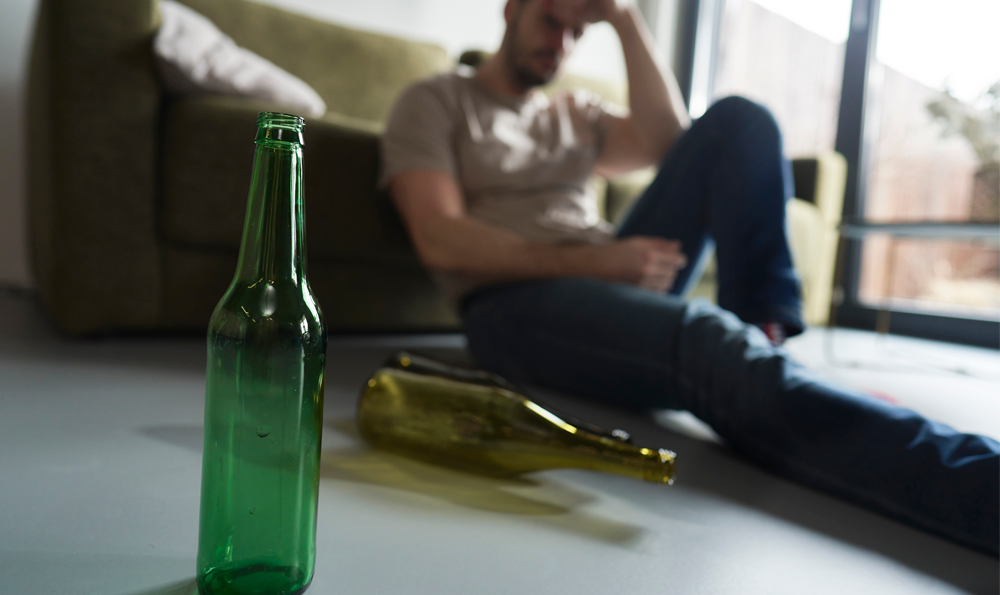 Man looks worriedly at empty alcohol bottles.