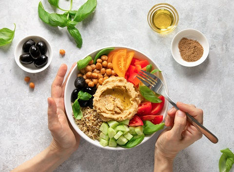 Vegetarian Buddha bowl with hummus, olives and quinoa, view from above