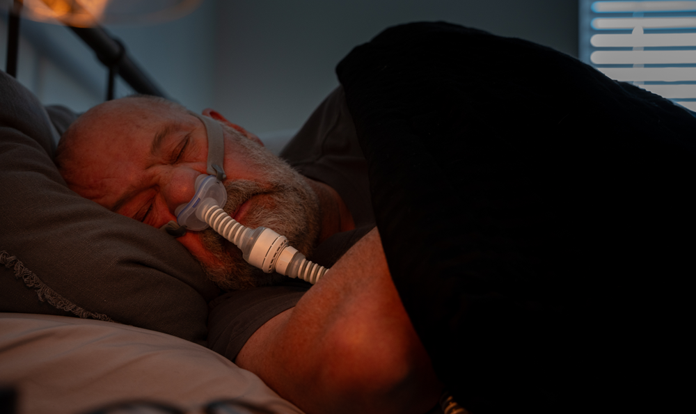 Man sleeping with a CPAP machine, due to obstructive sleep apnea.